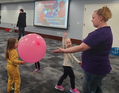 Two children and their grown-up play with a balloon.
