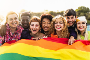 a group of diverse young adults holding a pride flag