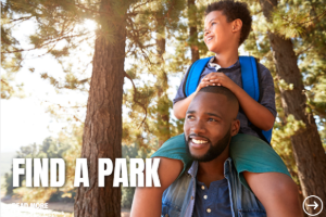 african american man with a young boy on his shoulders in the wilderness