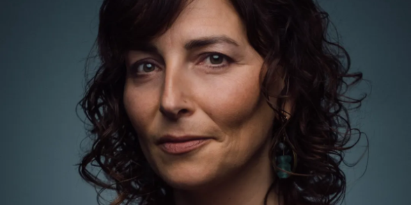 woman with brown curly hair looking at camera