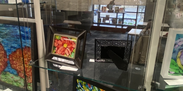 Display case with brightly colored alcohol ink paintings on glass.