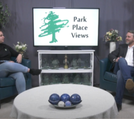 man and woman sitting in comfortable chairs laughing and talking in front of a screen that says Park Place Views