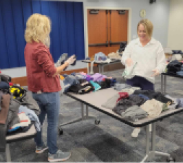 two women folding clothes for the clothing drive