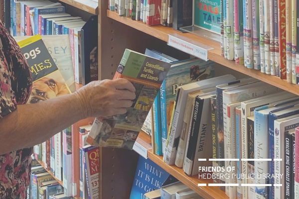 hand reaching for book on bookshelf