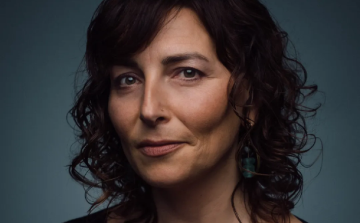 woman with brown curly hair looking at camera